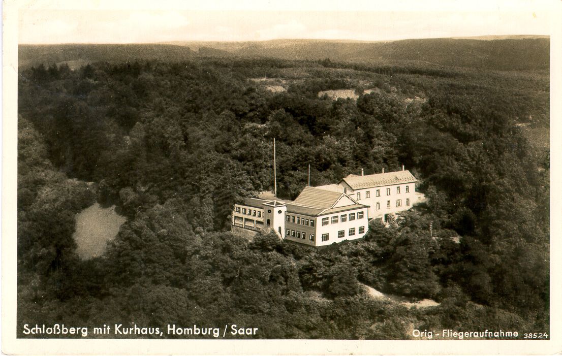 Historische Luftbild-Postkarte „Schloßberg mit Kurhaus, Homburg/Saar“: das Kurhaus inmitten dichter Wälder